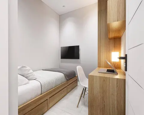 Ranjang dengan laci kayu dan meja kerja di sudut kamar